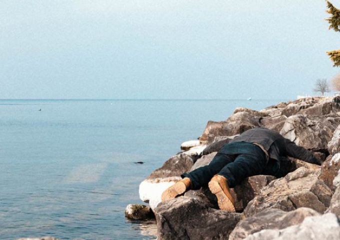 un homme allongé sur des rochers au bord de l'eau